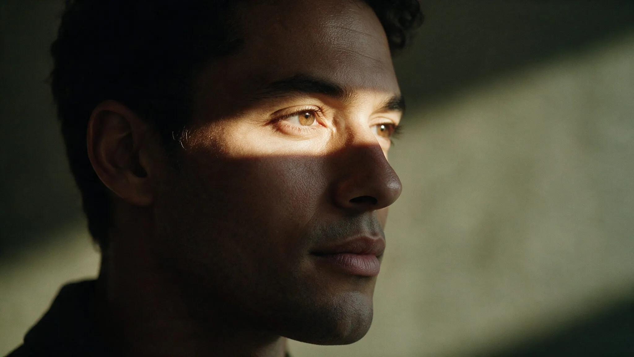 Rosto de homem com uma faixa de luz sobre os olhos, em ambiente escuro