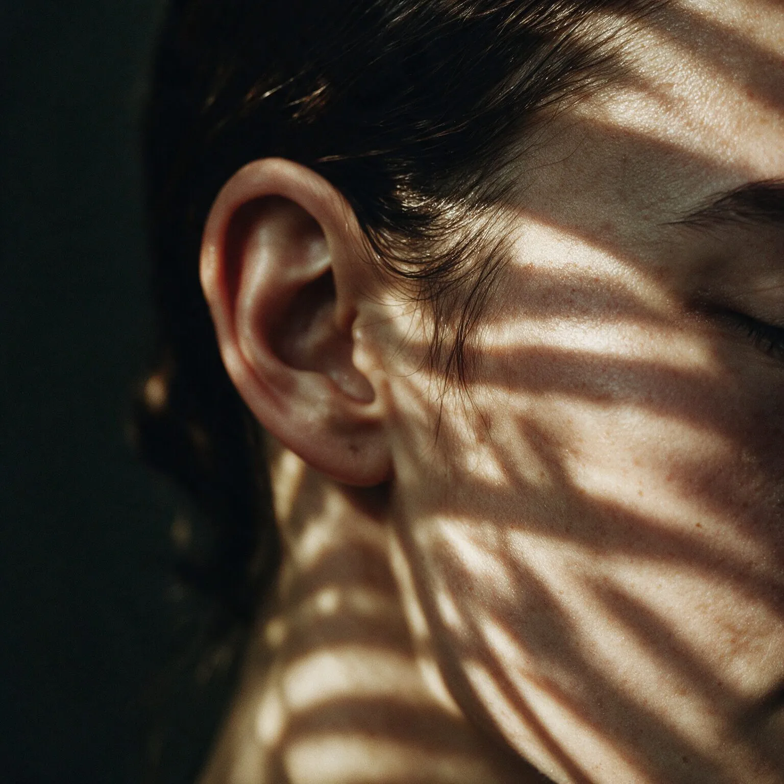 Perfil de mulher de olhos fechados com sombras de folhas sobre o rosto