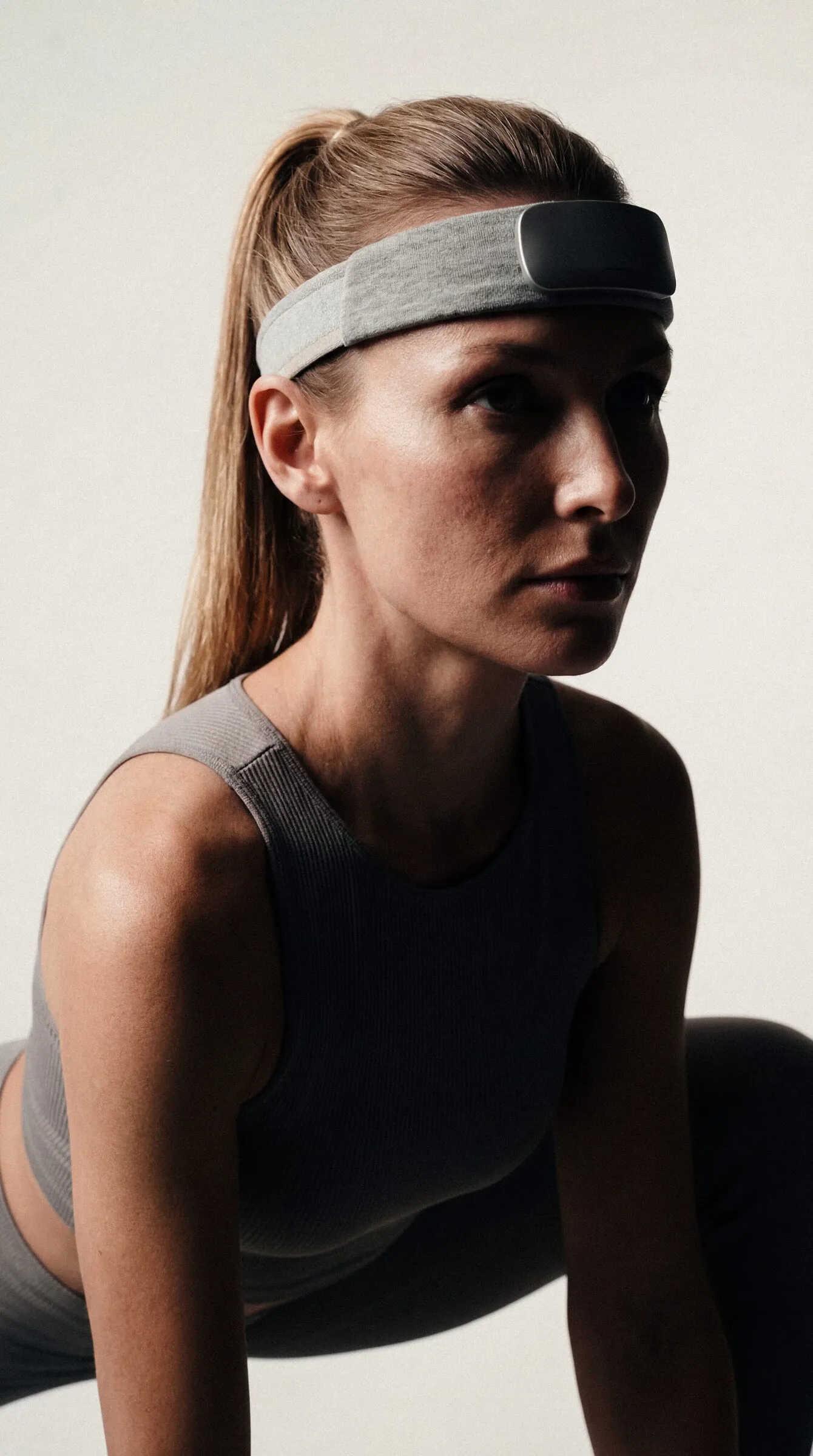Mulher de faixa de EEG na testa olhando para o lado, em roupa esportiva